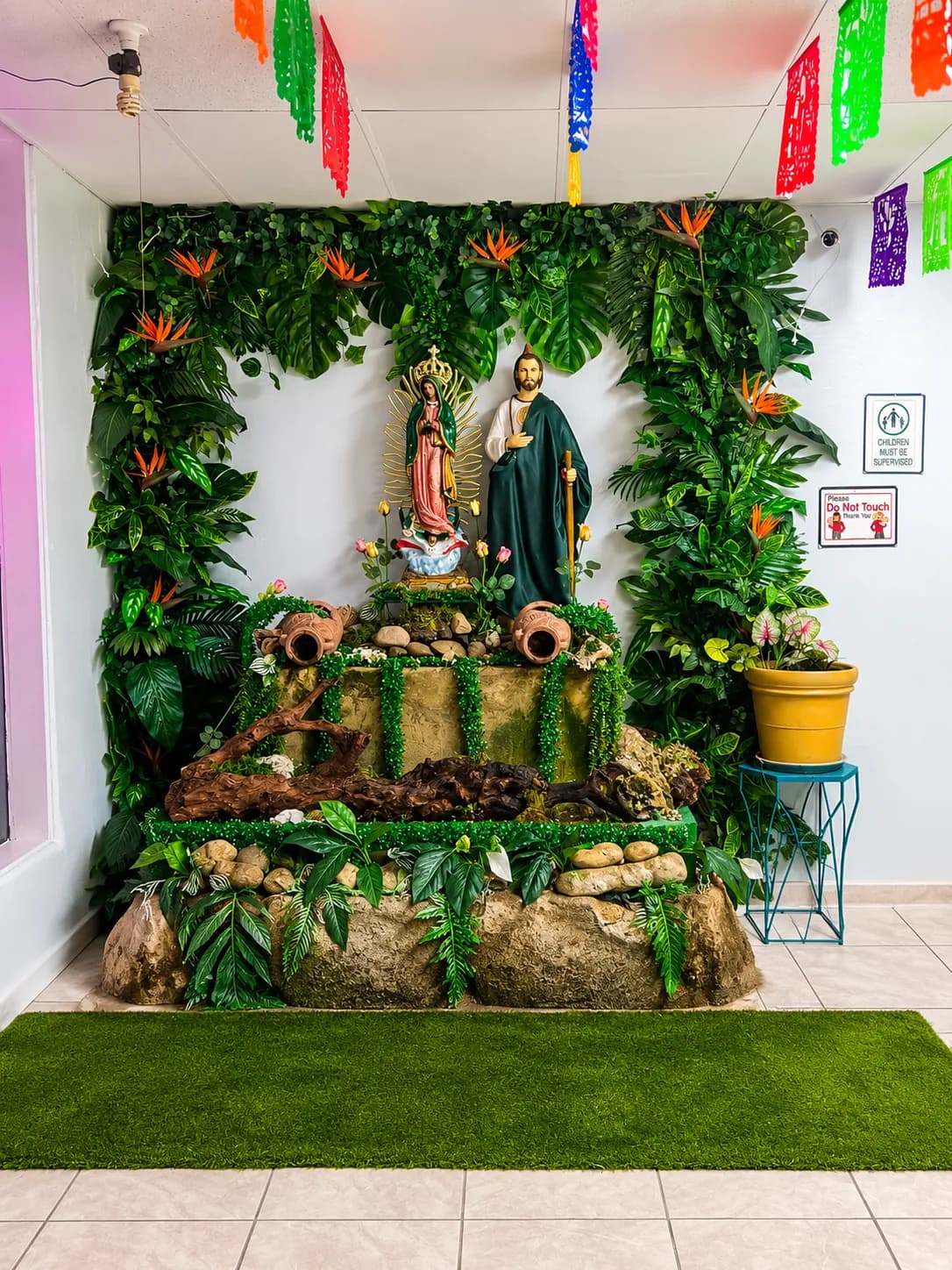 An indoor devotional display with the Virgen de Guadalupe surrounded by lush greenery inside Chilangolandia.